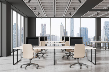 Office coworking interior with pc monitors on tables in row, panoramic window