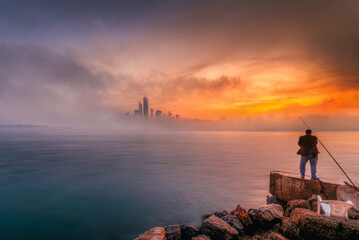 Abu Dhabi Cityscape and sky line in foggy morning with epic orange light of sunrise, taken from Abu Dhabi view point in the United Arab Emirates. 
