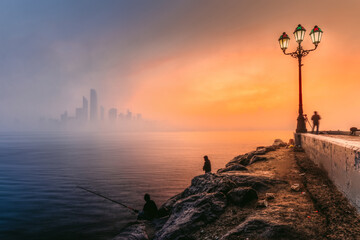 Abu Dhabi Cityscape and sky line in foggy morning with epic orange light of sunrise, taken from Abu Dhabi view point in the United Arab Emirates. 