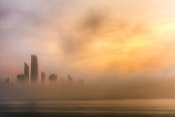 Abu Dhabi Cityscape and sky line in foggy morning with epic orange light of sunrise, taken from Abu Dhabi view point in the United Arab Emirates. 