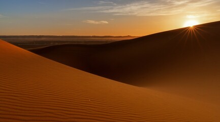 view of the sand dunes at Erg Chebbi in Morocco at sunset with a sunstar