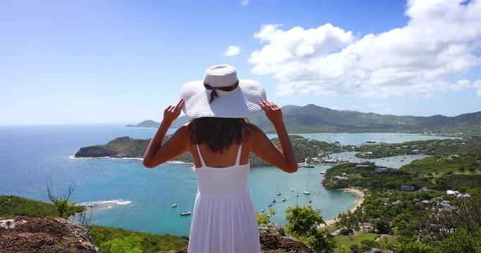 A tourist woman enjoys the panoramic view over the landscape of Antigua island with English Harbour and Shirley heights