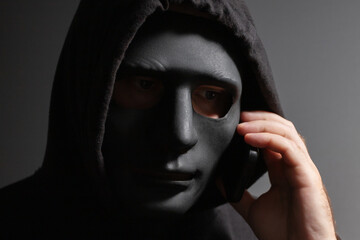 Robber, a man in a mask talking on the phone, gangster planning theft, masked criminal plotting...
