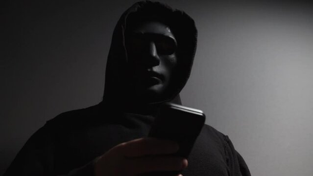 Man in a mask with a phone, thief, burglar, criminal.