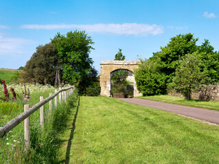 17th century arch frames the driveway to the parish church and the ruins of the 14th century...