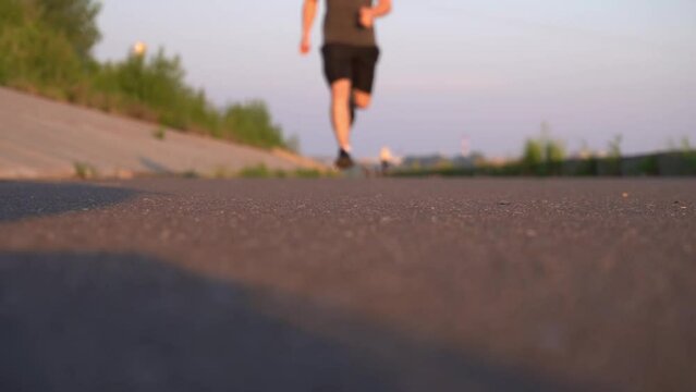 blurred sports background. slow motion. guy on the run is out of focus, active cardio training. jogging outdoors in summer.