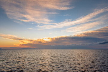 Sunset over ocean in wide angle view with reflection on water