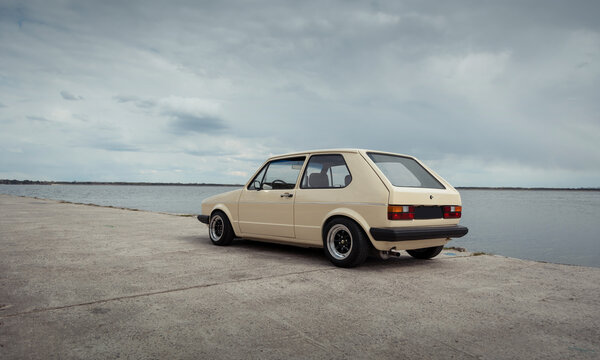 Beige classic Volkswagen Golf parked on concrete surface. Hatchback near the lake on a cloudy day. Kyiv region, Ukraine - April 18 2015.