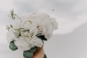A bouquet of white flowers is being held by a person. The flowers are arranged in a way that they look like they are in a vase. The bouquet is the main focus of the image.