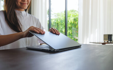 Closeup image of a woman opening or closing laptop computer, getting ready for work