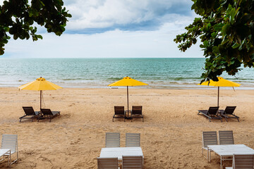 Yellow umbrella and black chair on beach