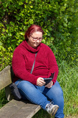 Obraz premium Woman reading a message on the phone in the park