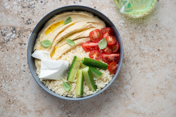 Mediterranean hummus bowl on a beige granite background, horizontal shot with space, view from above