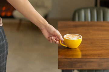 Woman hand holding coffee cup on table against city view in vintage cafe, select focus.