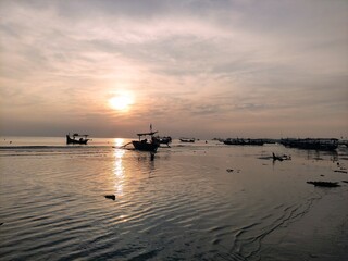 Naklejka premium silhouette of a ship anchored on the beach at sunset