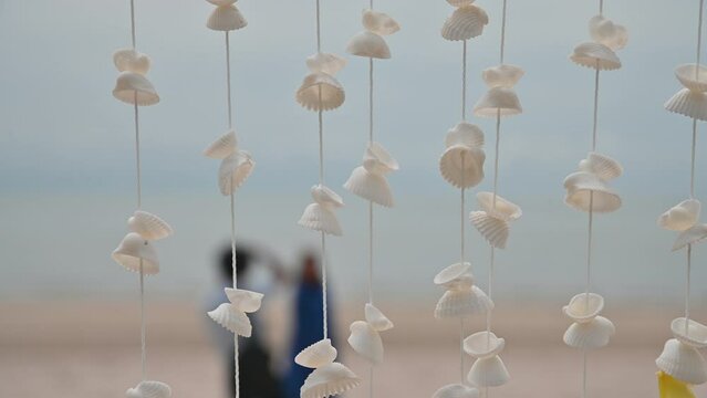 Moving of Seashells mobile hanging with light wind blowing on the beach. Beautiful handicrafts produced by sea shell