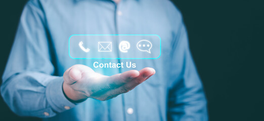 Customer support hotline with businessman using virtual screen contact icons for email, chat, and telephone. Online helpdesk advice and service support for business inquiries.