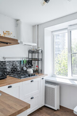 black and white kitchen. Kitchen with appliances, microwave, oven. wooden countertop in the kitchen. Metal sink, colorful glasses, mugs, knives.