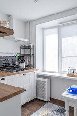 black and white kitchen. Kitchen with appliances, microwave, oven. wooden countertop in the kitchen. Metal sink, colorful glasses, mugs, knives.