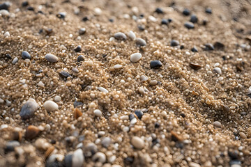 Beach pebbles close-up, sandy shore texture, mixed small stones, natural seaside background, coastal pebble surface, tranquil beach detail