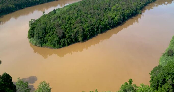A drone glides above a winding river cutting through the heart of a dense jungle, capturing the scene in all its natural splendor. The river's crystal-clear waters shimmer as they weave through the lu