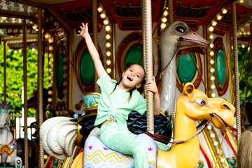 a child in an amusement park rides a carousel and enjoys the International Children's Day in...
