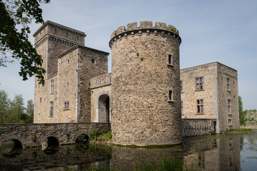 historic fortified building popular tourist attraction on sunny summer day. fresh water moat surrounds rural landmark structure near Liège