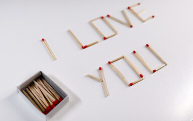 The inscription “I love you” is lined with matches next to the box. Macro. Wallpaper. 