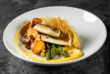 Pan-seared fish served on creamy puree, garnished with crispy potatoes, asparagus, and fried leeks, representing gourmet cuisine