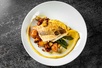 Pan-seared fish served on creamy puree, garnished with crispy potatoes, asparagus, and fried leeks, representing gourmet cuisine
