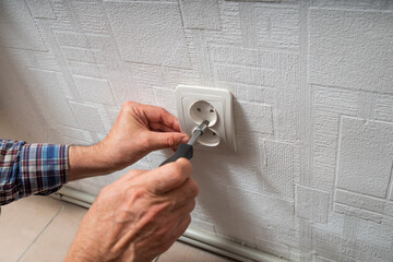 Installation or repair of electrical outlet socket box within the wall. Serviceman or repairman working with Socket type F European socket with grounding.