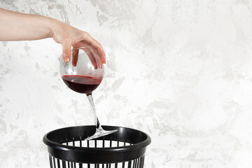 Quitting alcohol concept. Hand throwing wine glass into trash bin or waste bucket.