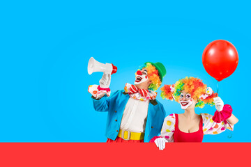 Funny clowns with baloon shouting with loudspeaker. Entertainer Joker in colorful suit and wig....