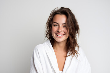 Fototapeta premium Young pretty brunette girl over isolated white background in a bathrobe