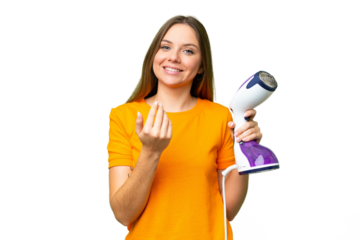 Young blonde woman holding a vertical steam iron over isolated chroma key background inviting to come with hand. Happy that you came