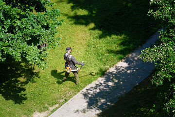 Man mowing grass, municipal worker cutting grass and maintaining public lawns for neat appearance....