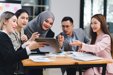Diverse business team actively collaborating and discussing ideas while using a tablet during an office meeting.