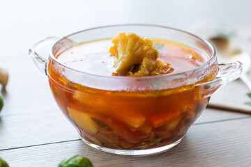 vegetable soup with Brussels sprouts and cauliflower, in a glass plate on a wooden table