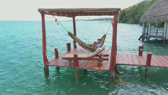 Young man relaxing in hammock in gazebo on the coast of Bacalar lagoon