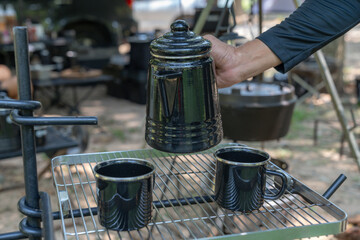 A picture of a hand pouring water from a kettle at campground
