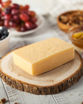 Tilsiter cheese block on chopped wood podium in kitchen