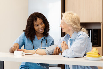 Nurse Checking Senior Woman's Blood Pressure At Home, Care And Support