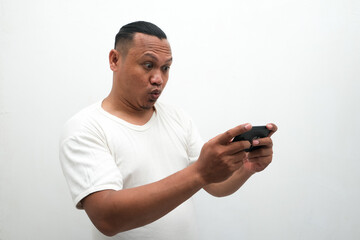 photo of the shocked expression of an Asian man looking at a mobile phone in his hand