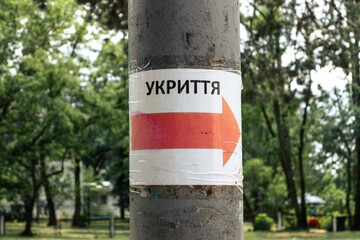 Signpost direction on the pillar to the bomb shelter in Ukrainian. The inscription in Ukrainian "SHELTER" on the pillar