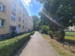 walking path in a parc with appartements to the side in Berlin Treptow/Köpenick on a very sunny day with sun beams 