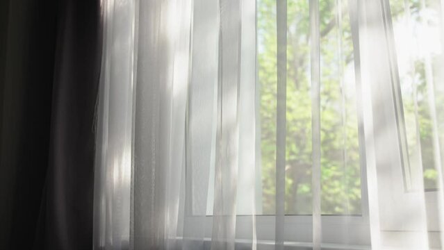 A cinematic shot of the sun glares on a tulle in the background of a window.