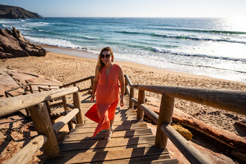 Beautiful woman walking on stairs to sunny beach Portugal, Algarve, Amado praia