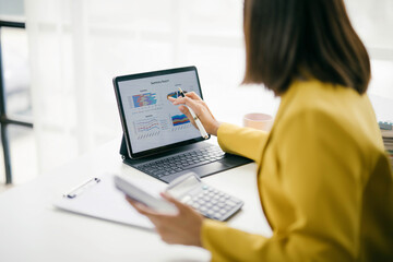 Businesswoman Analyzing Financial Data on Tablet with Stylus in Modern Office Setting