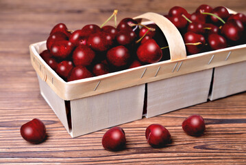 Ripe natural cherries, sweet cherries in a birch bark basket on a wooden background, selective focus