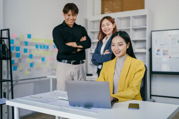 Obraz premium Young Professionals Collaborating in Modern Office Space with Laptop and Sticky Notes on Wall for Creative Brainstorming Session